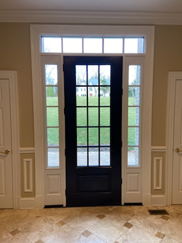 Black 15-lite glass front entry door with sidelights and transom viewed from the foyer.