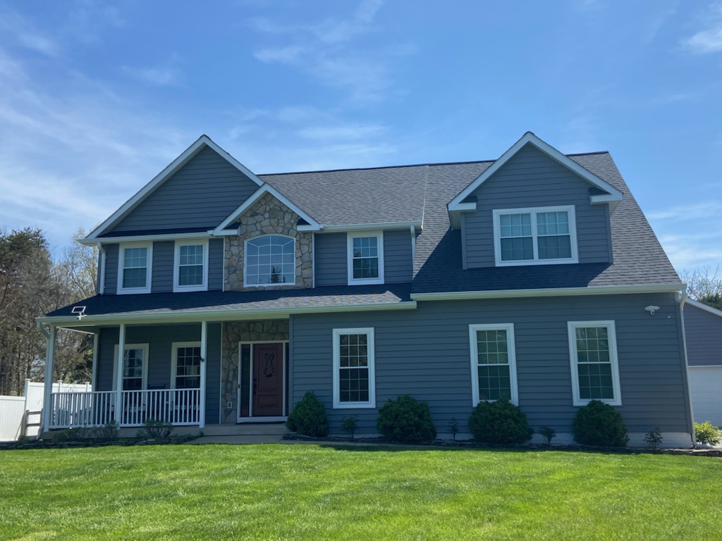 Two-story craftsman-style home with deep blue lap siding, stone accent, and a covered front porch.