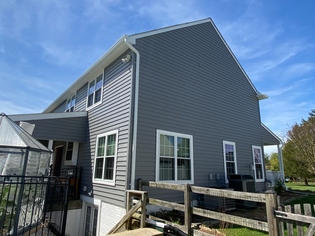 Side elevation of a gray lap-siding home with double-hung windows and architectural shingle roof.