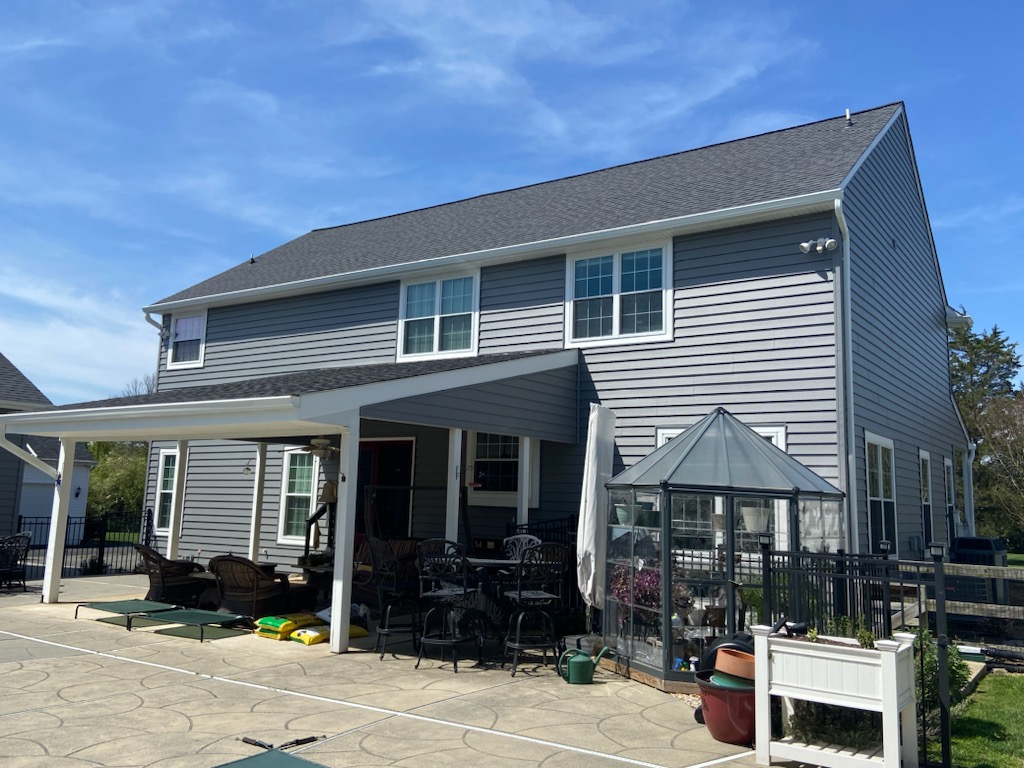 Rear elevation of a gray lap siding home with covered patio and architectural shingle roof.