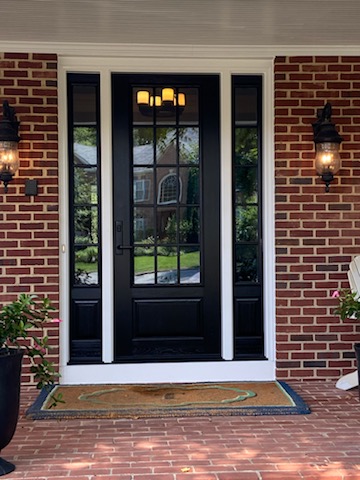 Black multi-pane front entry door with sidelights set into a brick home.