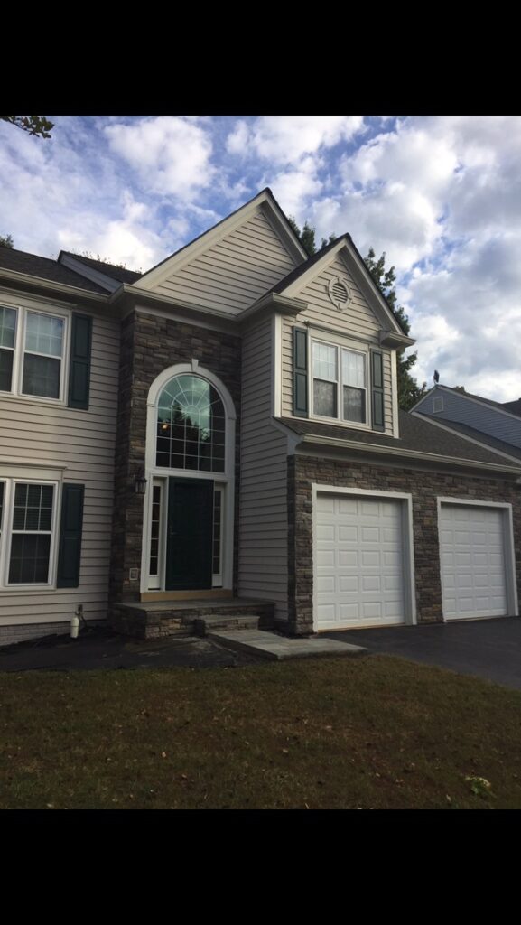 Two-story tan home with stone accent and arched palladian-style entry window above the front door.