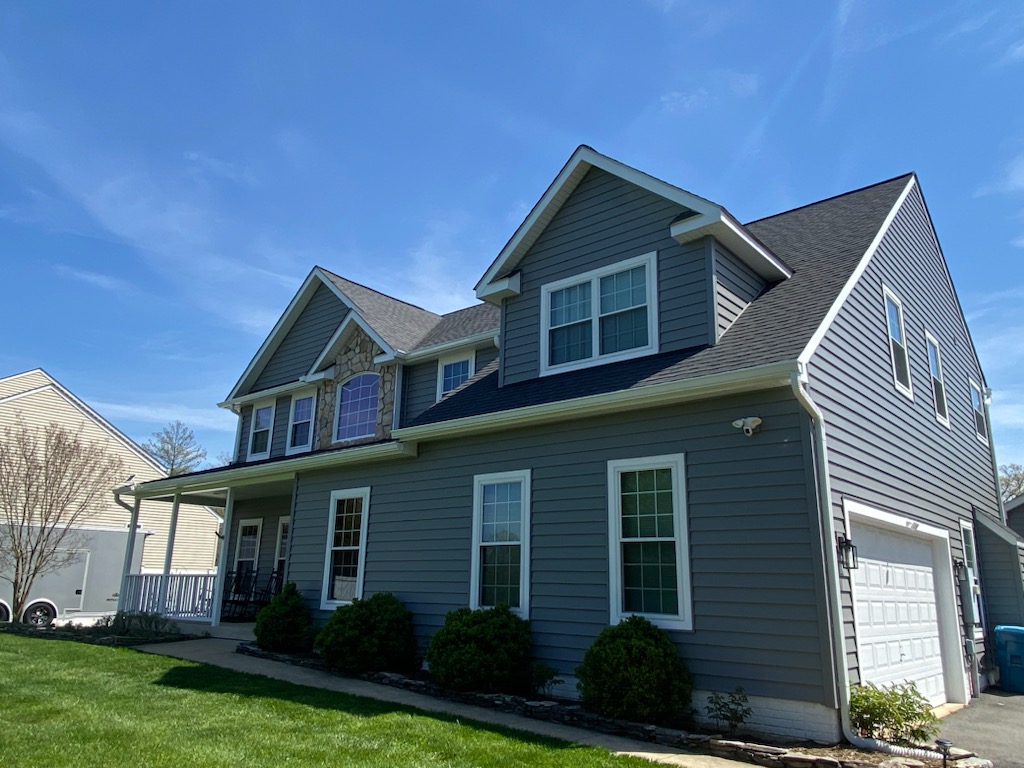 Two-story home with blue-gray lap siding, stone accent, and architectural shingle roof.