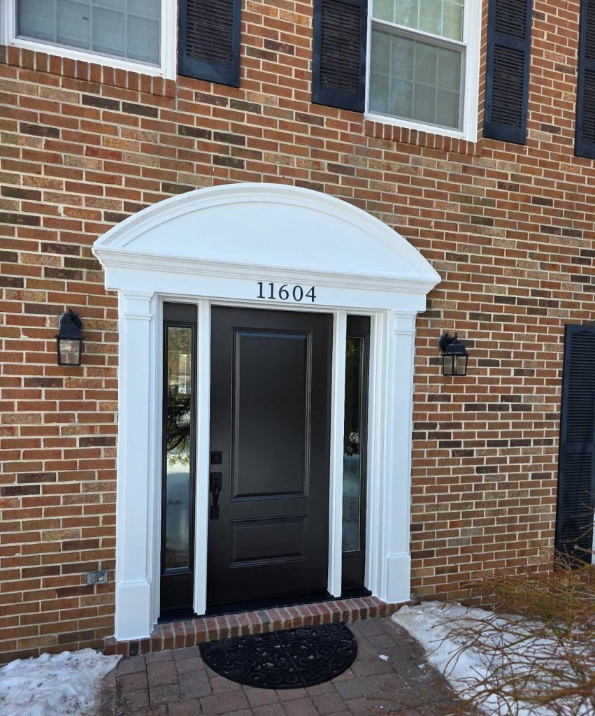 New black ProVia Legacy steel entry door and arched portico on a brick colonial after replacement