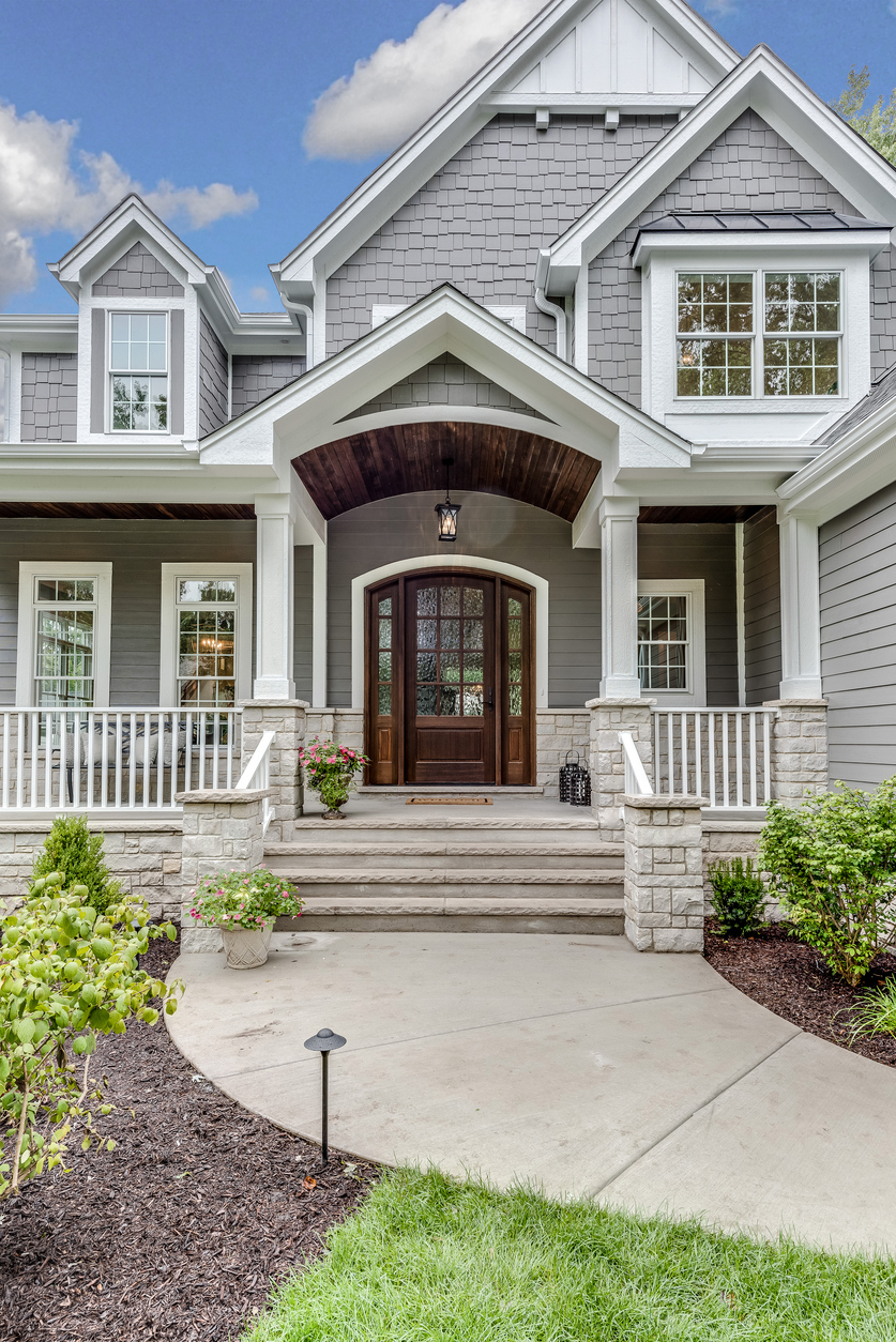 Covered front entry with a wood-and-glass door, sidelites, and stone porch columns