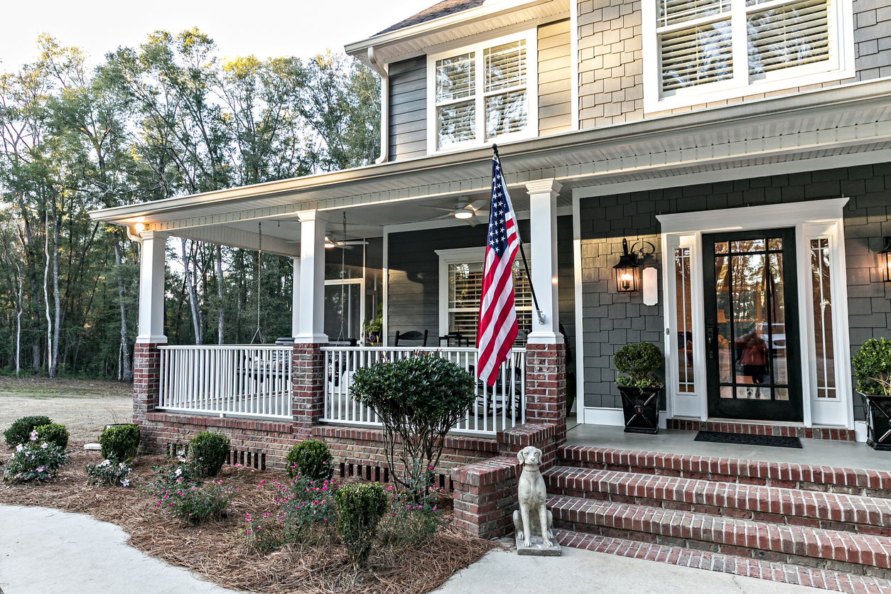 Shake-sided two-story with a wraparound porch on brick columns